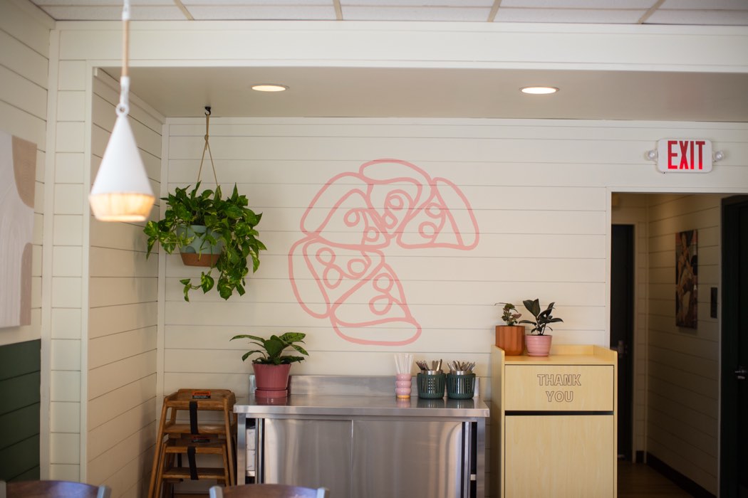 Inside the Barclay Pies dining room with the pink pizza mural and hanging plants